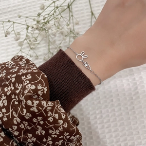 Detailed view of silver rabbit and carrot charms with diamonds on a delicate bracelet