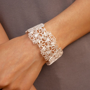 Detailed view of silver hollow flower cuff bracelet on wrist with elegant matte finish
