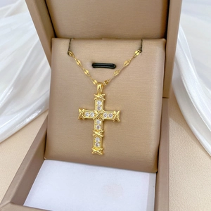 Elegant gold cross necklace with sparkling white diamonds on a white silk background