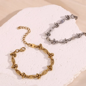 14K gold and silver plated coffee bean knot chain bracelets on textured stone base