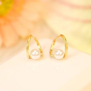 Detailed close-up of long tassel pearl earrings with gold metallic finish on a white surface