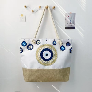 Close-up of canvas beach tote with thick rope handles and evil eye print detail