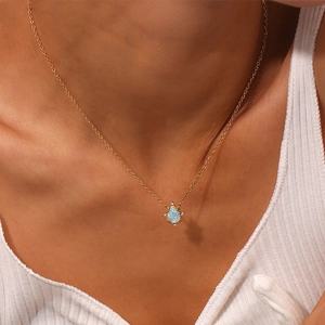 Close-up of gold necklace featuring a teardrop opal pendant with small accent stones