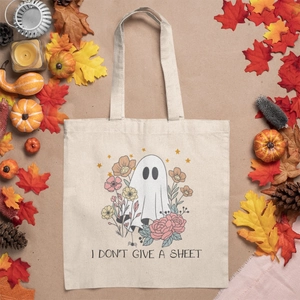 Close-up of canvas tote with Halloween ghost print and floral pattern on autumn background