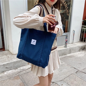 Detail shot of the large blue canvas tote bag featuring a white minimalist logo patch