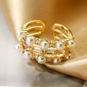 Adjustable gold plated open ring with pearls and zircon on silk champagne fabric