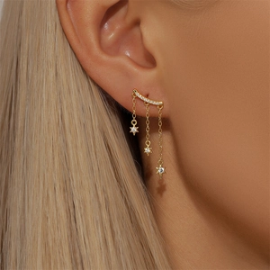 Close-up of golden tassel earrings with star pendants and zircon stones worn by a model