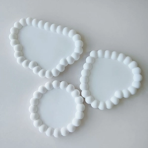 Flat lay of bubble textured white silicone coaster molds in round and irregular cloud shapes