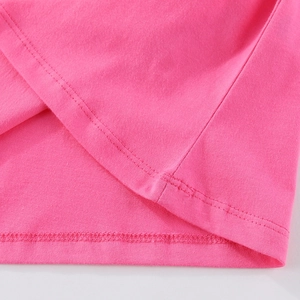 Détail de couture à double aiguille sur l'ourlet d'un haut en coton rose pour filles