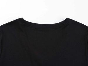 Close-up detail of the reinforced V-neck stitching on this slim-fit black cotton t-shirt
