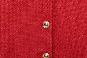 Detailed close-up of red tweed fabric texture with gold round metal buttons