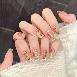 Detail van roze-gouden verloop plaknagels met blad-steentjes en parels op lange kistvorm