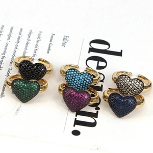 Adjustable gold rings with colorful heart-shaped zircon stones on vintage paper