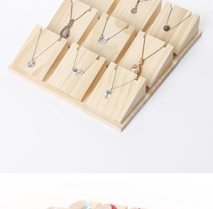 Macro view of solid wood tiered necklace display stand with natural wood grain texture