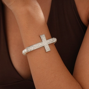 Close-up of a luxury Baroque pearl bracelet with a shimmering pavé crystal cross charm