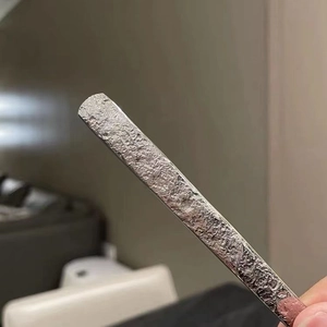 Close-up of silver stainless steel spoon showing hammered stone texture and polished finish