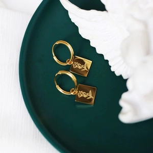 French style gold-plated coin earrings with embossed rose pattern on dark green tray