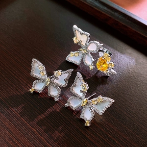 Detailed close-up of butterfly jewelry set with zircons and shell inlay on wood