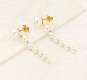 Macro detail of gold stainless steel pearl tassel earrings with S.Steel hallmark engraving