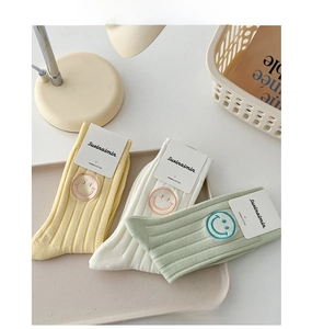 Detail of three pastel combed cotton mid-tube socks featuring smiley face embroidery