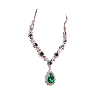 Elegant silver necklace set with pear-cut green gemstone and white diamonds on white background
