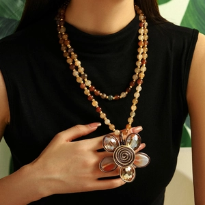 Detail of double-layer beaded necklace featuring a large vintage floral pendant on a black top