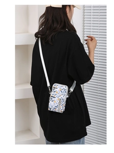 Rear view of a floral crossbody phone bag with leaf patterns on a female model