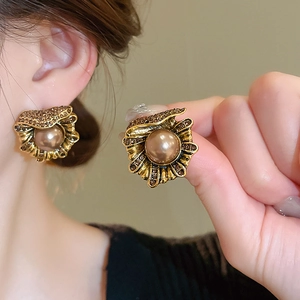 Détail macro de la boucle d'oreille fleur vintage avec perle brune et strass brillants