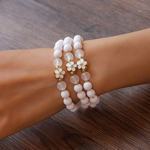 Detailed close-up of a three-piece acrylic beaded bracelet set with gold floral charms