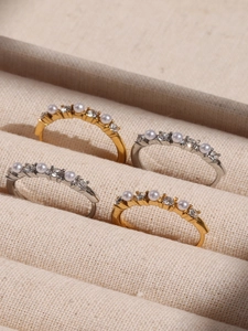 Detail of gold and silver stackable rings with pearls and crystals in a beige jewelry box
