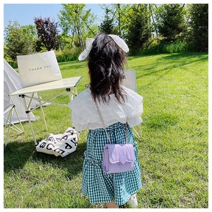 Bambina che indossa borsa a tracolla trapuntata lilla con fibbia a cuore al parco