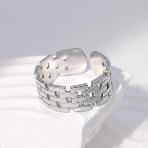 Modern hollow brick pattern open ring in polished silver stainless steel on a white stone base