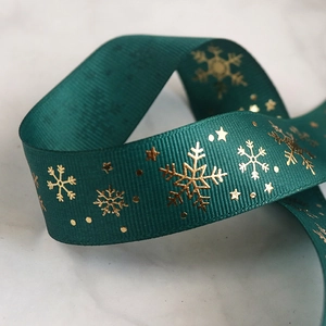 Close-up of green ribbed Christmas ribbon with gold snowflake and star foil patterns