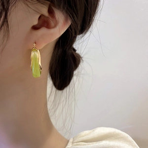 Close-up of elegant gold U-shaped earrings with green translucent inlay on model