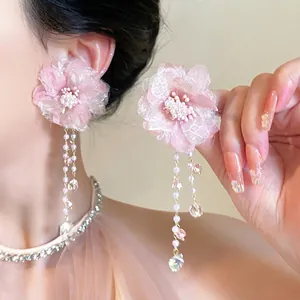 Detail of pink floral earrings with delicate organza petals and pearl bead tassels