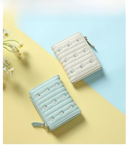Detail of short wallets with daisy embroidery and quilted pattern in cream and mint