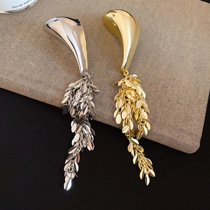 Detailed close-up of metallic leaf tassel earrings in elegant gold and silver finishes