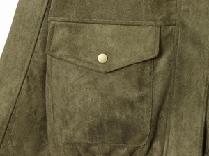 Close-up detail of olive green faux suede jacket showing flap pocket and bronze metal button