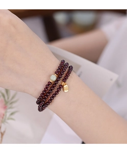 Detail of red garnet multi-wrap bracelet with green jade bead and gold Fu charm
