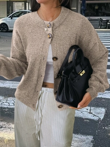 Détail d'un cardigan en maille couleur chameau avec fermeture à boutons sur le devant