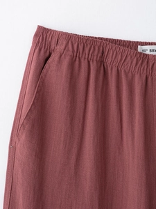 Detail of dark red cotton linen trousers with elastic waist and side pockets