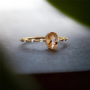 Macro shot of gold ring with oval champagne gemstone and small side diamonds
