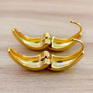 Detailed close-up of golden teardrop hoop earring hinges on a wooden background