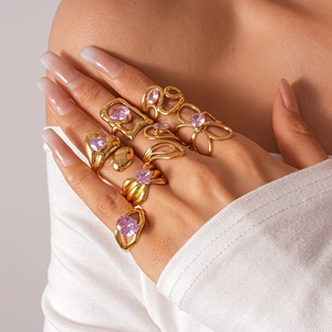 Stacked gold alloy rings featuring purple zircon stones on a model hand with heart motifs
