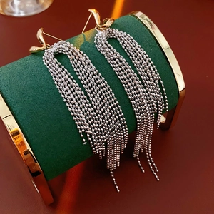 Close-up of 18k gold plated wave stud with long silver bead chain tassels on a velvet stand