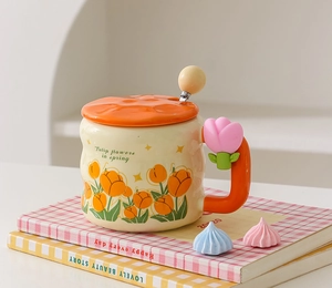 Detail of a beige ceramic mug with orange tulip pattern and pink floral handle on books