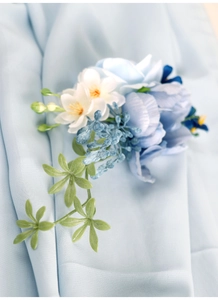 Macro shot of blue and white silk corsage flower with delicate leaves and pearl detail