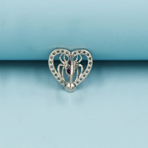 Macro shot of silver heart-shaped belly ring with spider motif and clear crystal pavé
