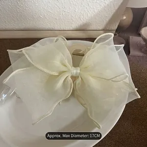 Detail of cream mesh hair claw clip with 17cm diameter pearls on a white plate