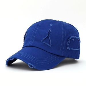 Close-up of distressed ripped details on a navy blue cotton canvas baseball cap
